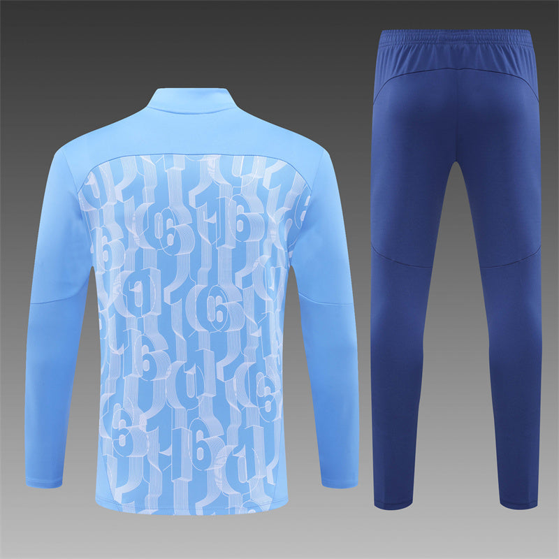 Close-up of Man City badge on the blue 24/25 tracksuit.